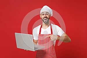 Excited young bearded chef cook or baker man in striped apron t-shirt toque chefs hat isolated on red background