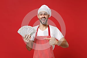 Excited young bearded male chef cook or baker man in striped apron toque chefs hat isolated on red background. Cooking