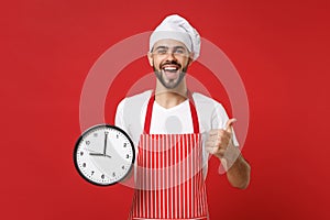 Excited young bearded male chef cook or baker man in striped apron white t-shirt toque chefs hat isolated on red