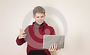 Excited young boy wearing casual clothing holding and using open laptop standing isolated over white background