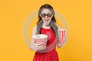 Excited young brunette woman girl in red summer dress, 3d glasses isolated on yellow background. People lifestyle
