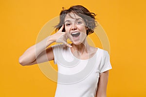 Excited young brunette woman girl in white t-shirt posing isolated on yellow orange background studio portrait. People