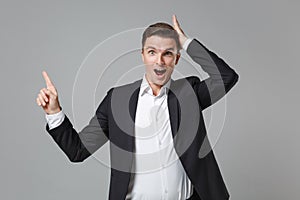 Excited young business man in classic black suit shirt isolated on grey wall background. Achievement career wealth