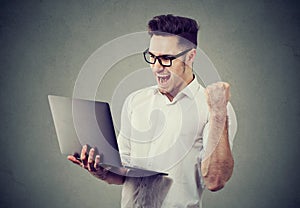 Excited man with laptop computer celebrating success photo