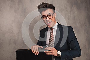 Excited young business man sitting and holding briefcase