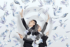 Excited young business man and woman with dollars under money rain