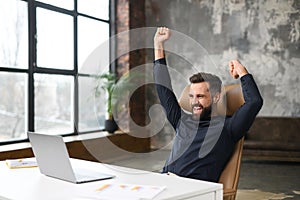 Excited young businessman in smart casual wear celebrating successful deal