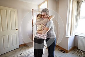 Excited Young Couple Hugging By Front Door Of New Home