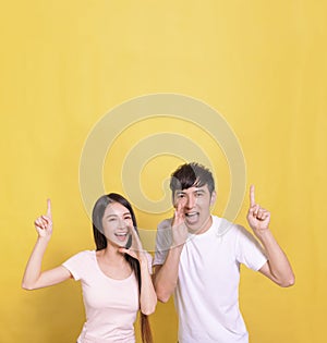 Excited young couple screaming and pointing up