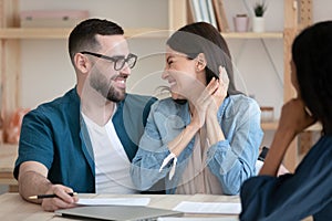 Excited young couple sign deal at office meeting