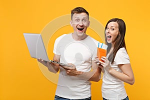 Excited young couple two friends in white t-shirts posing isolated on yellow orange background. People lifestyle concept