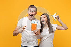 Excited young couple two friends in white t-shirts posing isolated on yellow orange background. People lifestyle concept