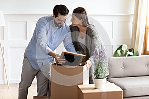 Excited young couple unpack boxes settle at new home