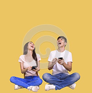 Excited young couple using mobile phone and looking above