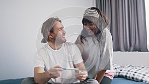 Excited young couple waiting for results of pregnancy test. Positive test. Multiracial couple expecting baby