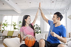 Excited Young couple watching tv and  raising hands to celebrating the victory