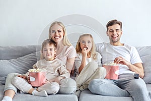 excited young family watching movie on couch