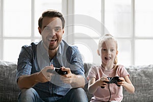 Excited young father and little girl playing video games