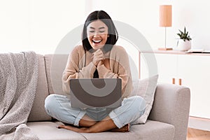 Excited young female feeling ecstatic using laptop