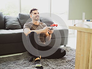 Excited young handsome man playing video game and keeping mouth open while sitting on the couch at home