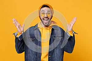 Excited young hipster guy in fashion jeans denim clothes posing isolated on yellow orange background studio portrait
