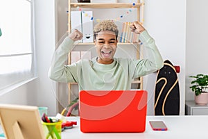 Excited young hispanic latin man celebrating good news using laptop at home