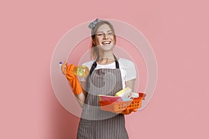 Excited young housewife wearing apron posing with cleaning tools in hands