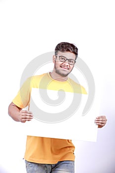 Excited Young Indian man on spectacles and showing blank poster in hand