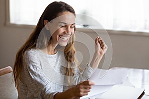 Excited young lady reading postal letter of loan request approval