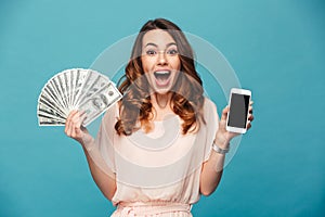 Excited young lady showing display of mobile phone holding money.