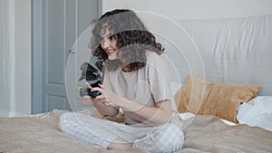 Excited young lady wearing pajamas enjoying video game having fun in bed at home