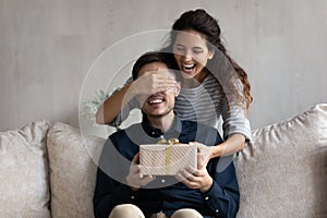 Excited young Latin woman giving surprise gift to excited boyfriend photo