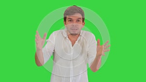 Excited young man in casual clothes looking into camera telling a story and gesturing on a Green Screen, Chroma Key.