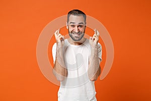 Excited young man in casual white t-shirt posing isolated on orange background in studio. People lifestyle concept. Mock