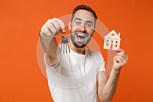 Excited young man in casual white t-shirt posing isolated on orange background studio portrait. People sincere emotions