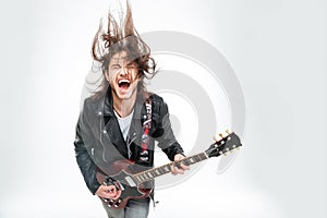 Excited young man with electric guitar shouting and shaking head
