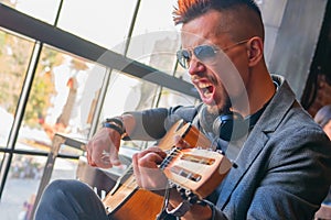 Excited young man with guitar singing and shouting