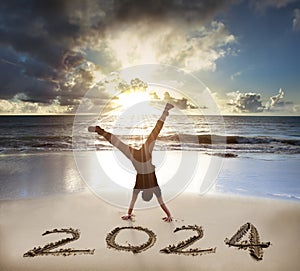 Excited Young man handstand on the beach.happy new year 2024 concept