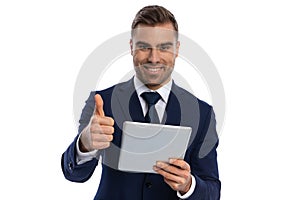 excited young man holding tab and making thumbs up gesture