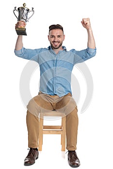 Excited young man holding trophy and celebrating