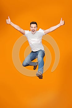 Excited Young Man Jumping, Celebrating Success Over Studio Background