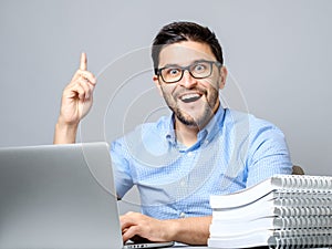 Excited young man with laptop pointing finger up