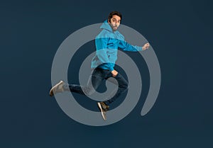 Excited Young Man Man Jumping In Air On Blue Background