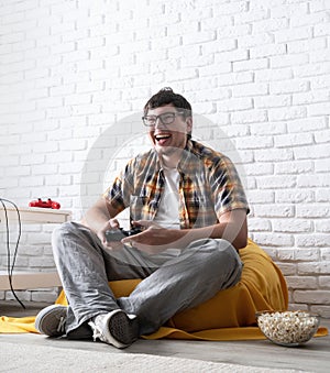 Excited young man playing video games at home and laughing