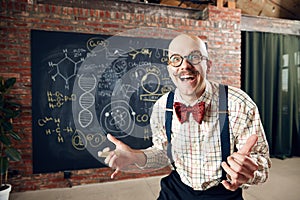 Excited young man, scientist feeling happy and delightful, successful researchers. Formulas on blackboard