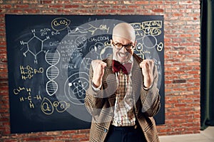 Excited young man, scientist feeling happy and delightful, successful researchers. Formulas on blackboard