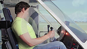 Excited young man sitting in flight simulator, turning controls on cockpit deck