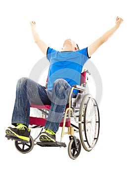 Excited young man sitting on a wheelchair and raising hands