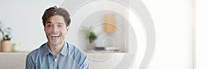 Excited young man smiling at camera, home interior