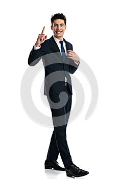 excited young man in suit walking, adjusting suit and pointing finger up